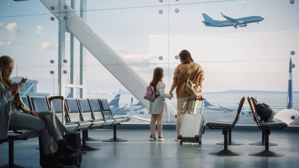 Mother and daughter waiting with luggage inside an airport | Hemmat Law Group